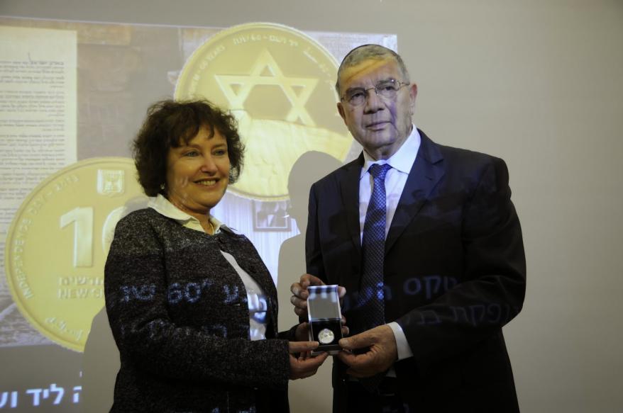 Yad Vashem Chairman Avner Shalev being presented the anniversary coin by the Governor of the Bank of Israel Dr. Karnit Flug 